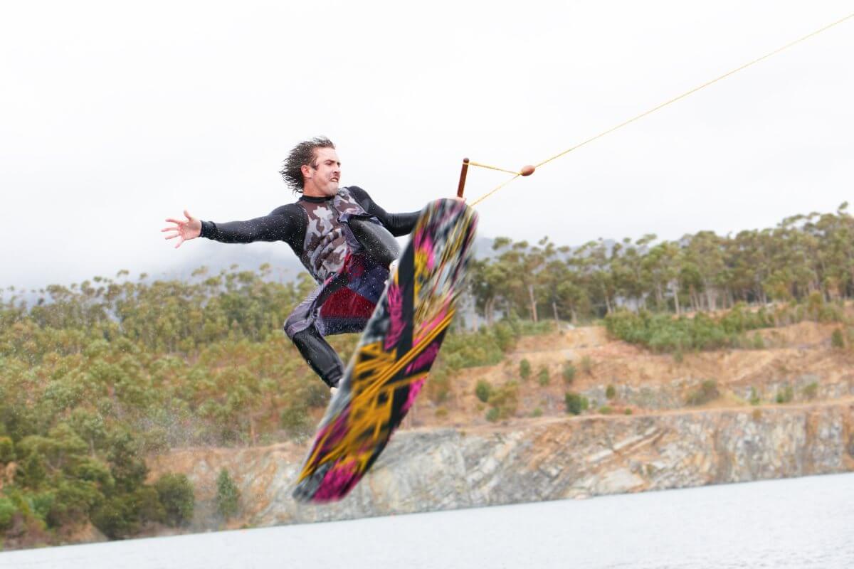Guy on a wakeboard doing a trick on the lake