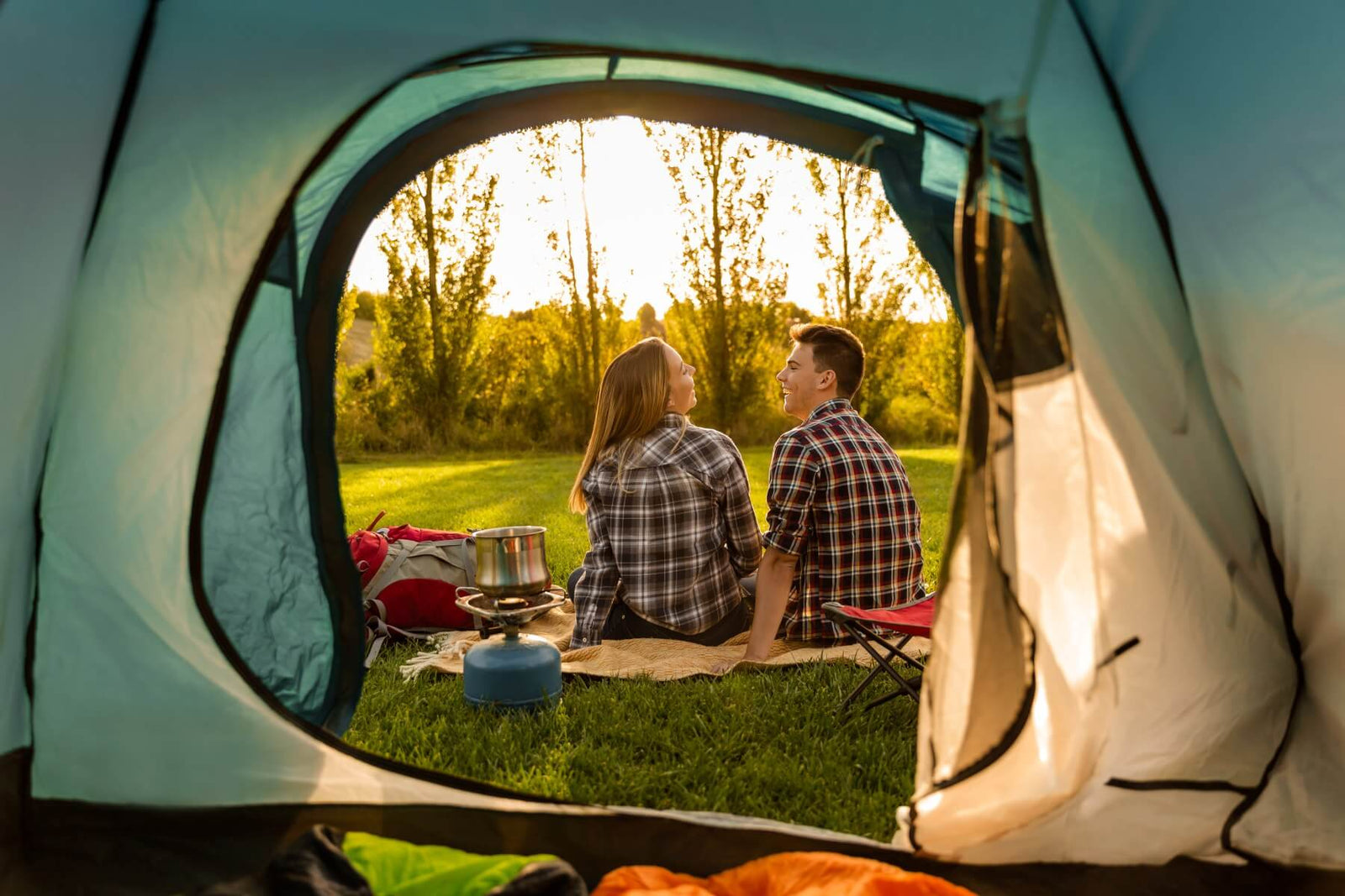 camping in the outdoors sitting outside of a tent